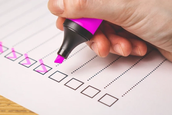 Person using a pink highlighter to check off items on a checklist
