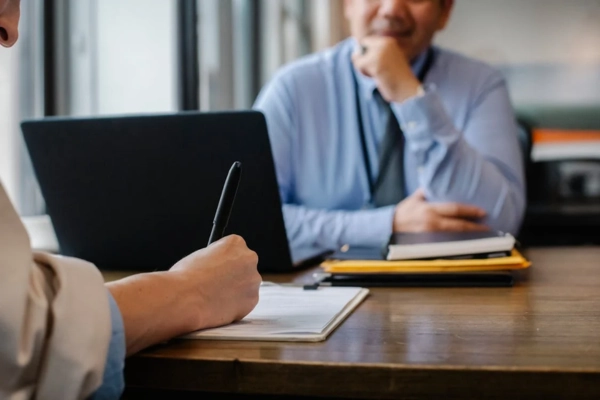 Close-up of a person writing notes during a meeting with a fractional CTO