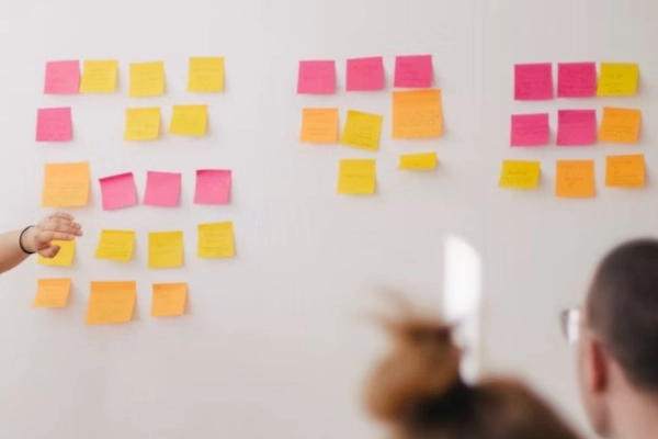 A business meeting with a person speaking in front of a Scrum board