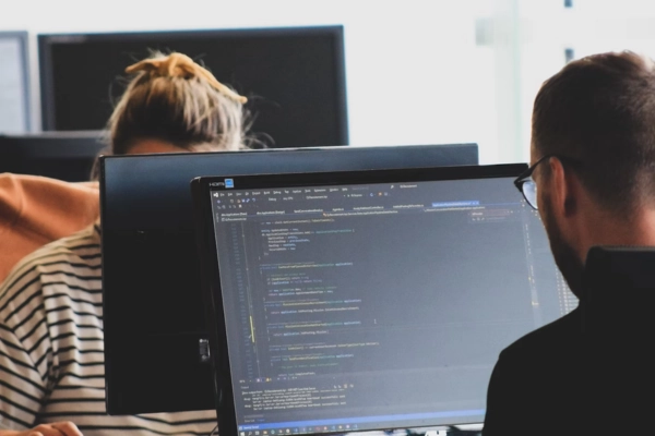 Two software developers working at computer screens, with code displayed on the monitor