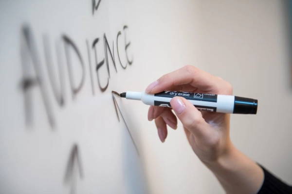 A founder writing the word “Audience” on a whiteboard with a marker