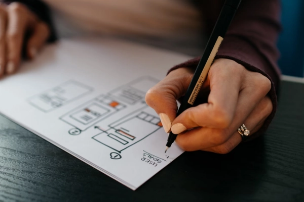 A person is sketching a wireframe design for a website or mobile application