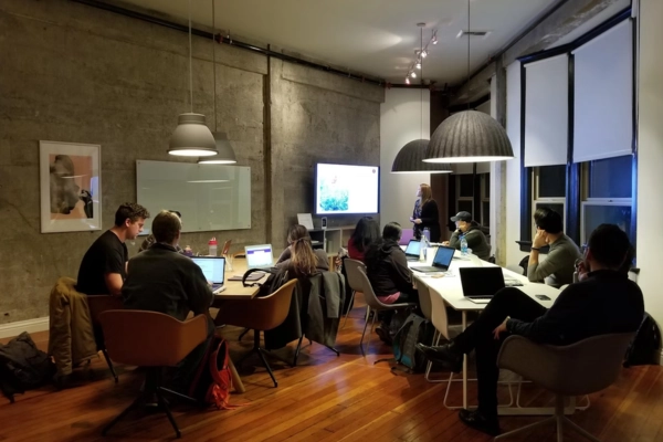 A software team collaborating in a modern office setting with laptops and a large screen for brainstorming