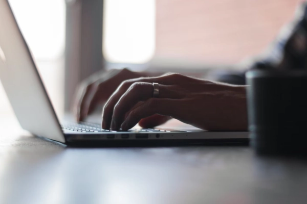 Close-up of hands typing on a laptop keyboard in a softly lit environment