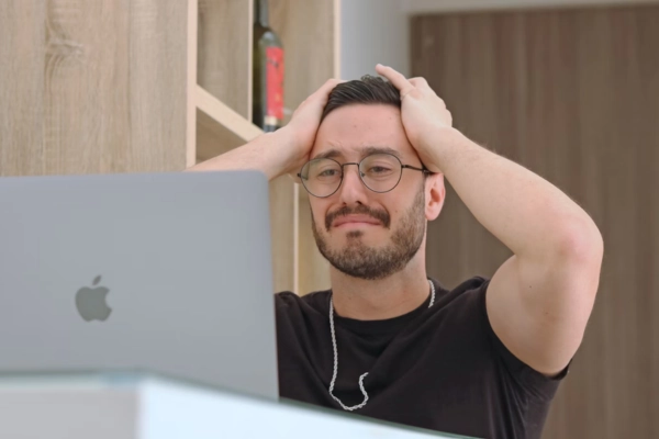 A stressed-out software engineer with hands on his head, reacting to coding issues