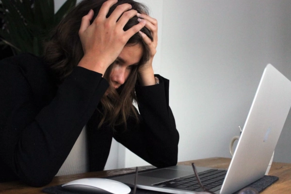 Stressed woman holding her head while looking at a laptop