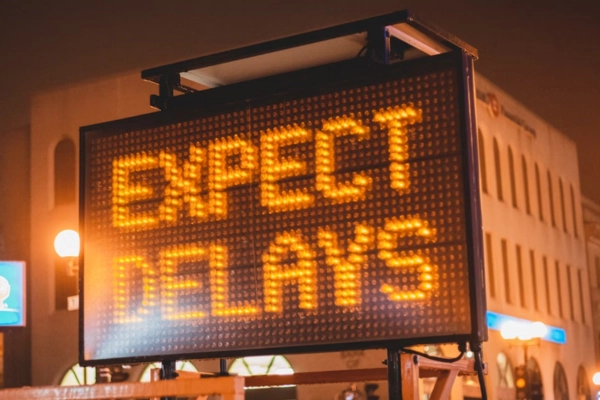 Digital road sign displaying “Expect Delays” at night