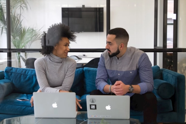 Two team members discussing work with laptops in a modern office
