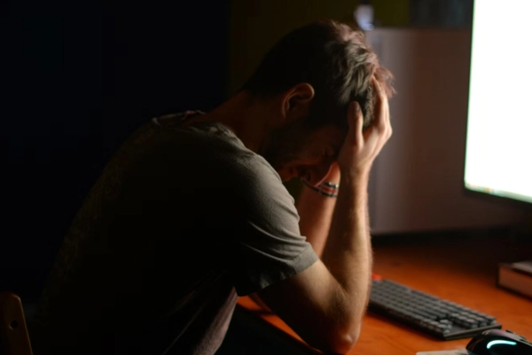 Frustrated man at desk, holding head in hands
