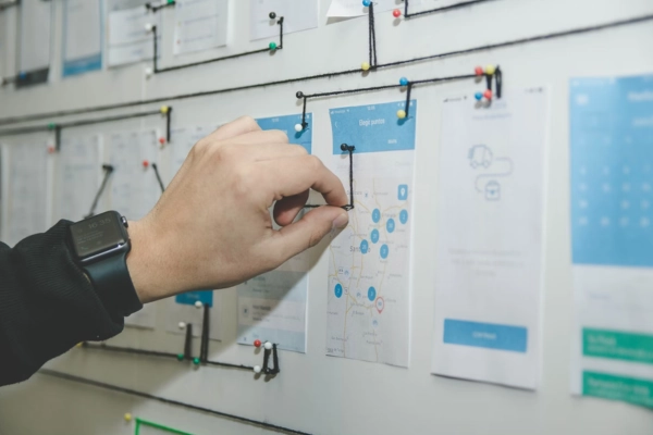 Hand adjusting a UX flow on a wall of mobile app screens