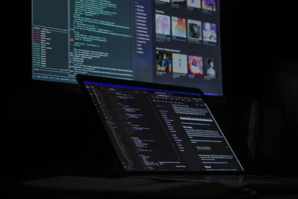 Laptop with code editor and second screen showing media library