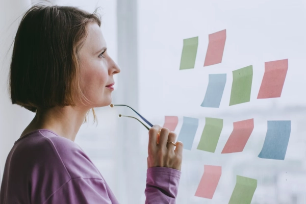 Person thinking and planning with sticky notes on a glass wall