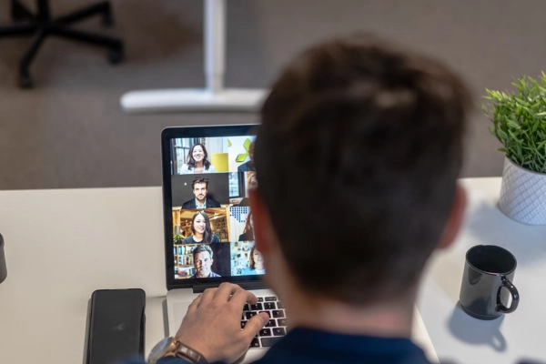 Professional participating in a virtual meeting with external team members on a laptop screen